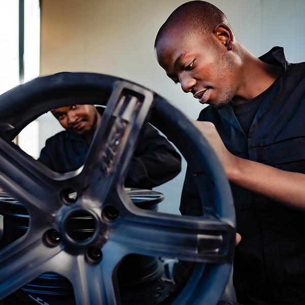 Two wheel collision technicians repairing alloy wheels